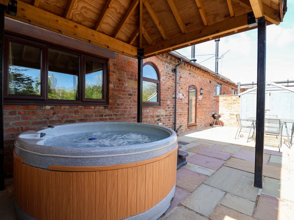 A hot tub with a surrounding patio area at Clwyd Cottage St Asaph