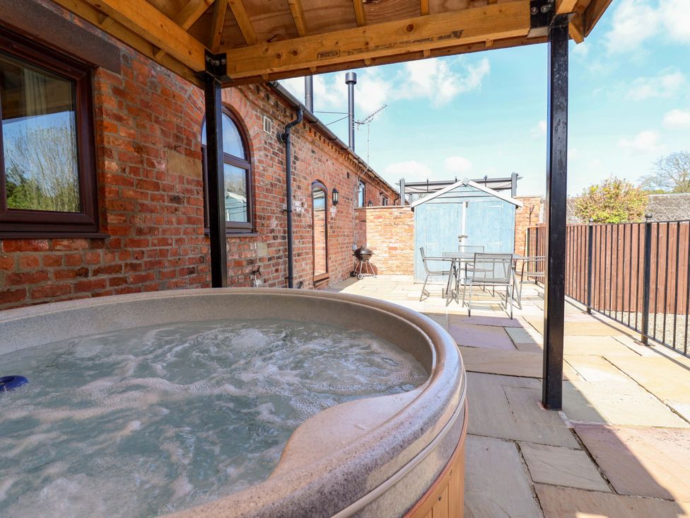 A hot tub with outdoor furniture and a shed at Clwyd Cottage St Asaph