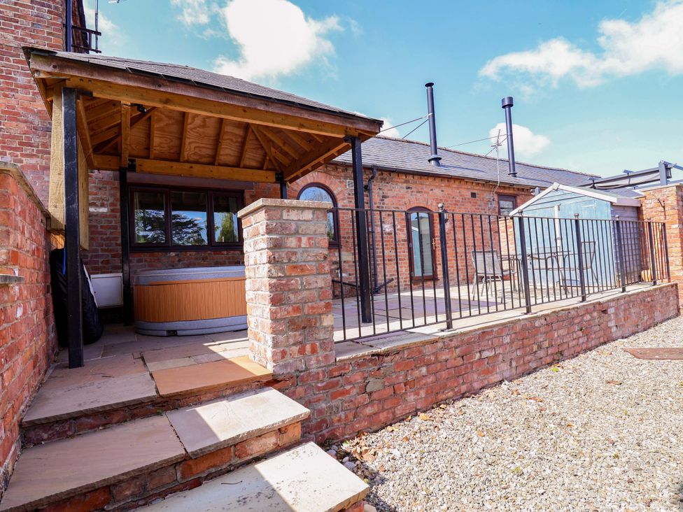 A garden with a hot tub and patio area at Clwyd Cottage St Asaph
