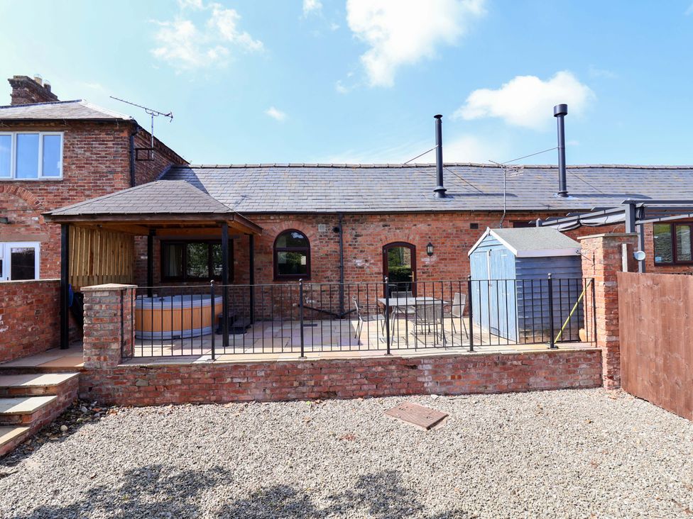 An outdoor area with a hot tub and patio furniture at Clwyd Cottage in St Asaph