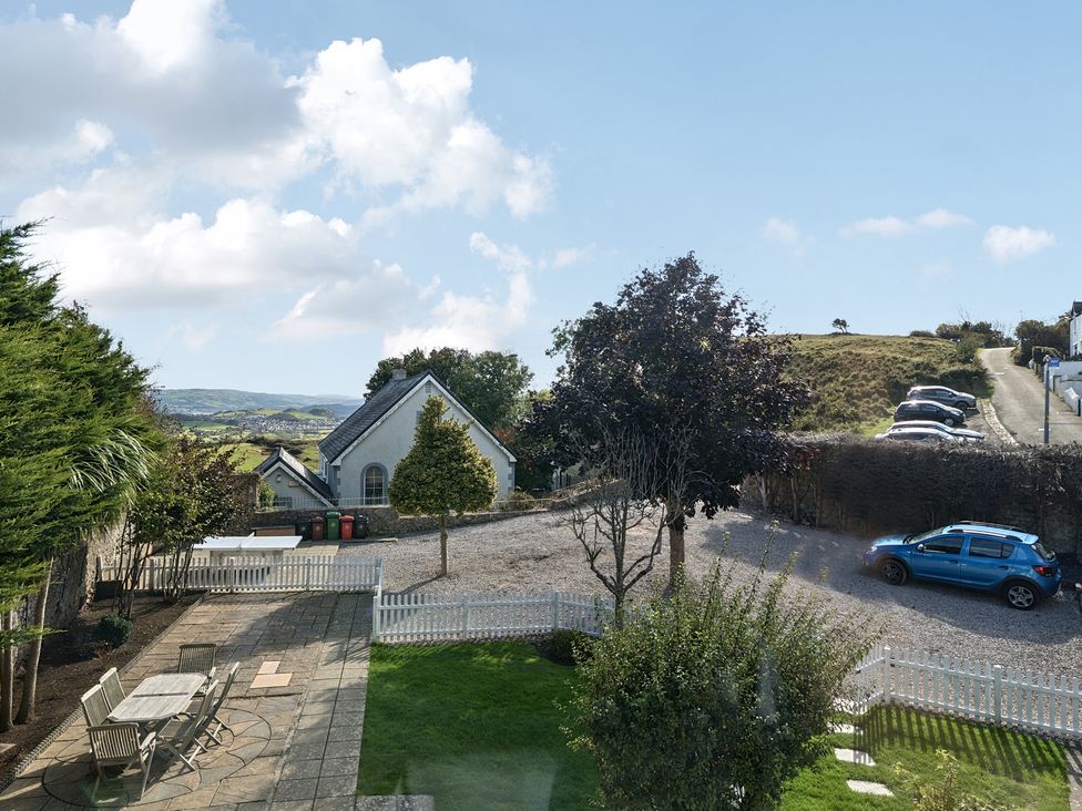 An outdoor view showing a house, parking area, and garden at Ty Mawr, Great Orme in Llandudno