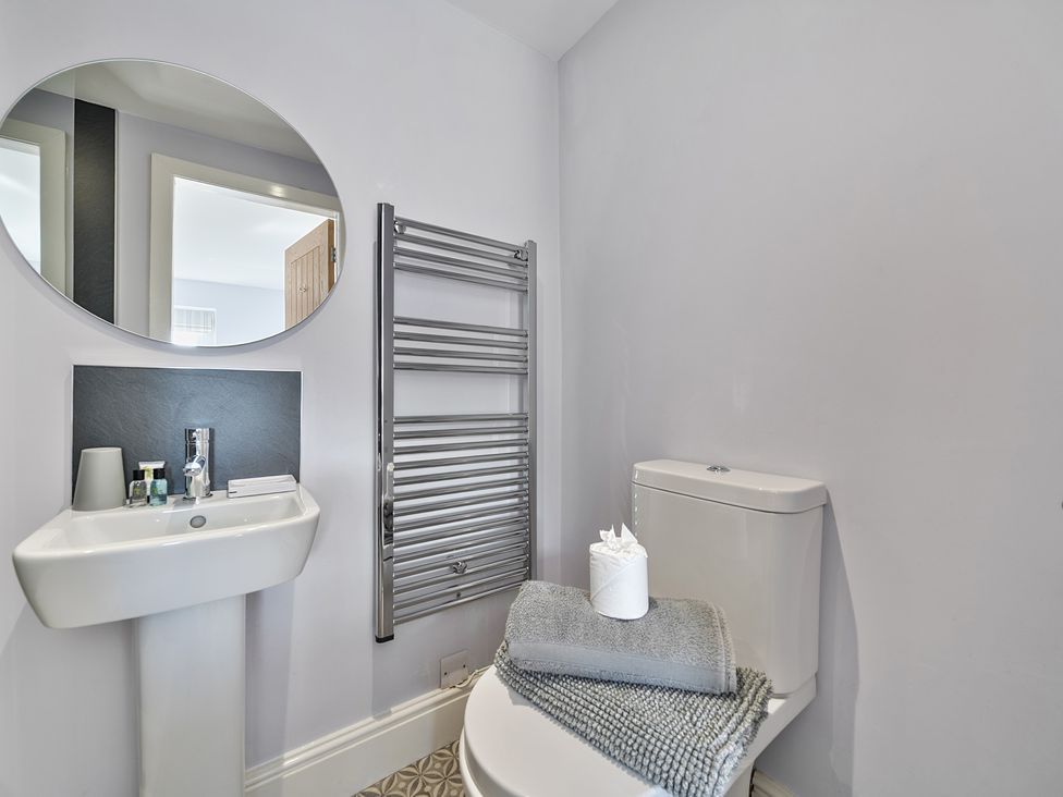 A bathroom featuring a toilet, sink, mirror and towel radiator at Ty Mawr, Great Orme in Llandudno