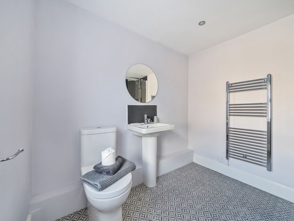 A bathroom with a toilet, sink, mirror, and towel rack at Ty Mawr, Great Orme, Llandudno