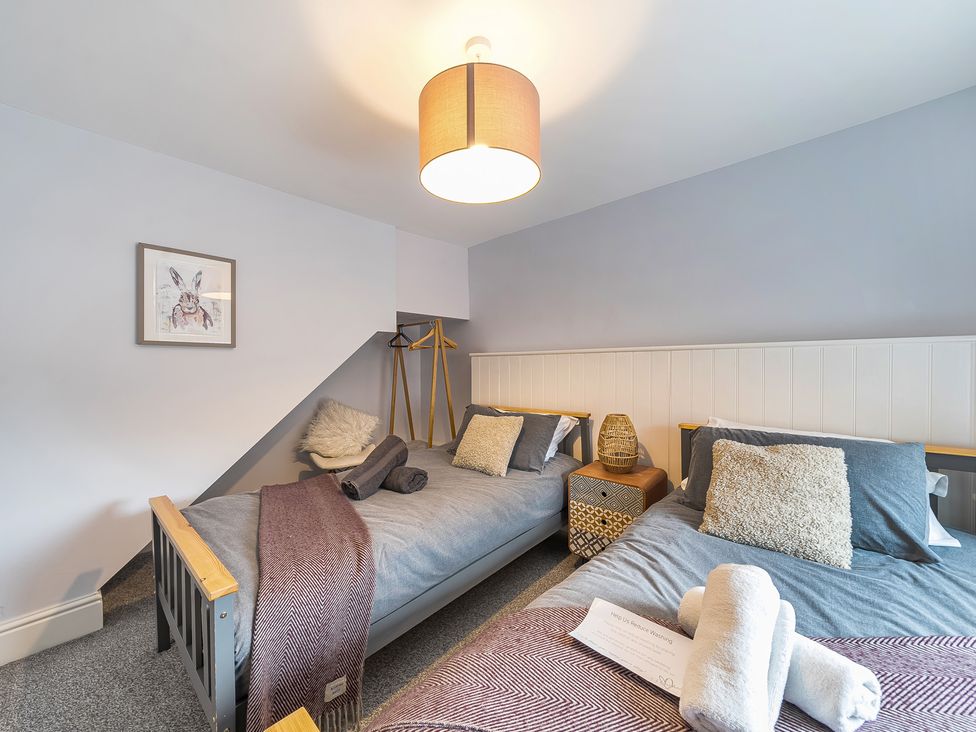 A bedroom with two beds and a side table at Ty Mawr, Great Orme in Llandudno