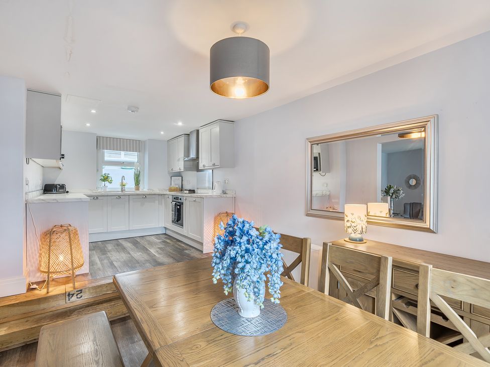 A dining room with a table and flowers at Ty Mawr, Great Orme in Llandudno