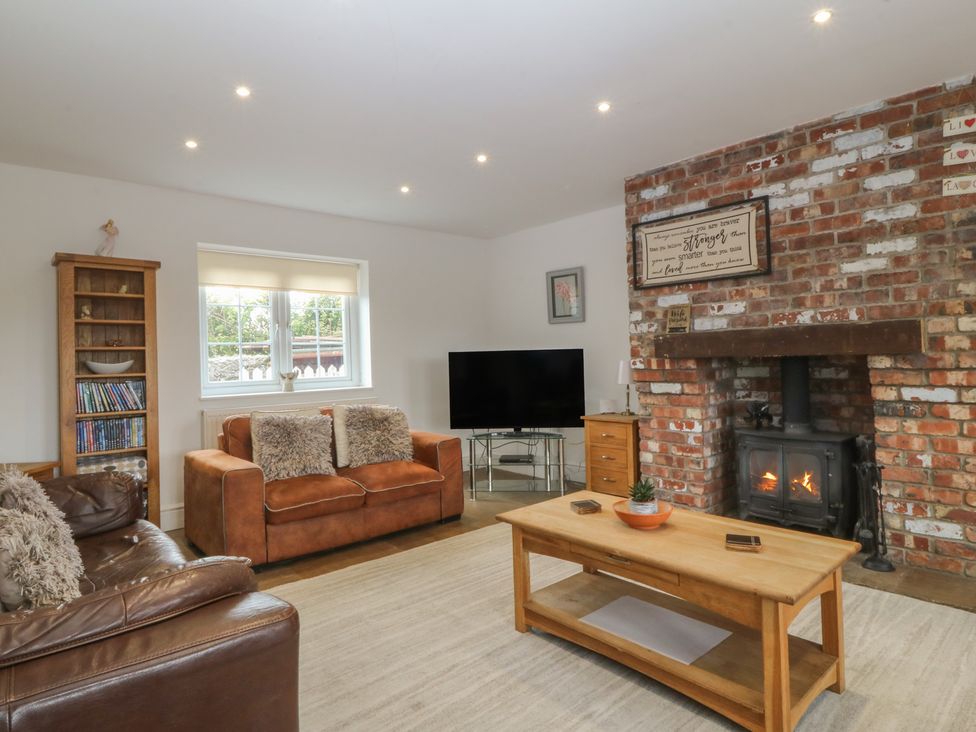A living room with a fireplace and sofa at Llanallgo Church Rooms