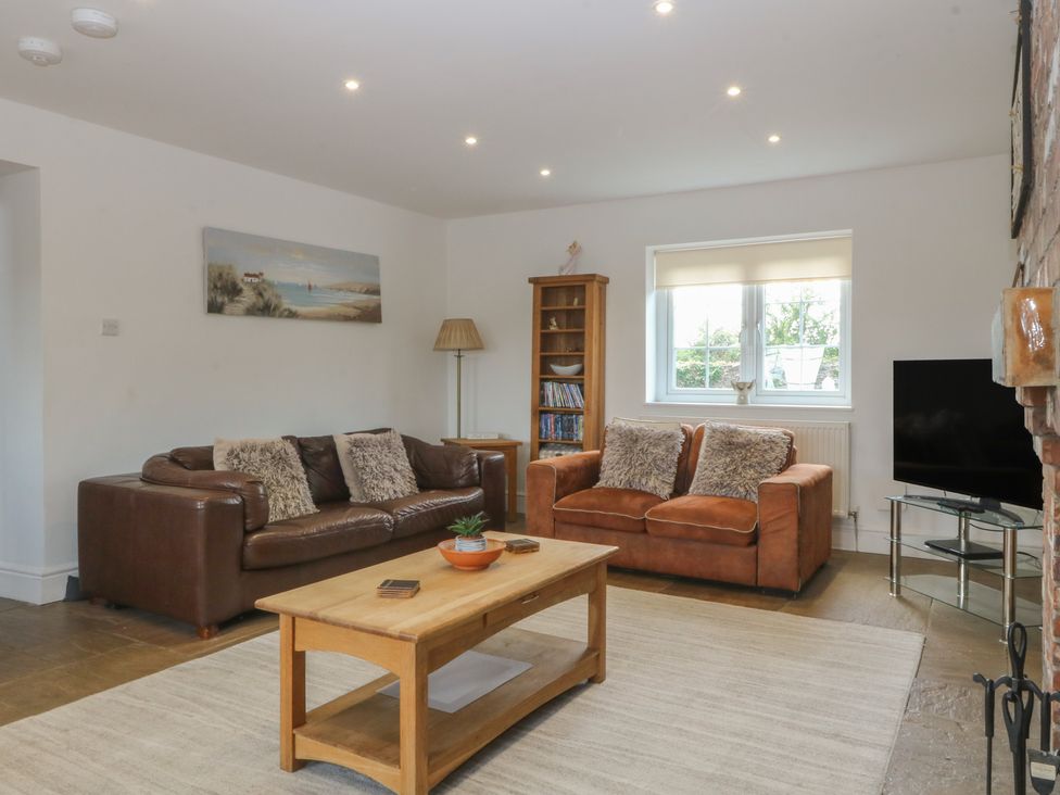 A living room with sofas, a coffee table, and a television at Llanallgo Church Rooms in 