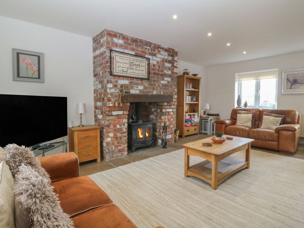 A living room with a sofa, fireplace, and TV at Llanallgo Church Rooms