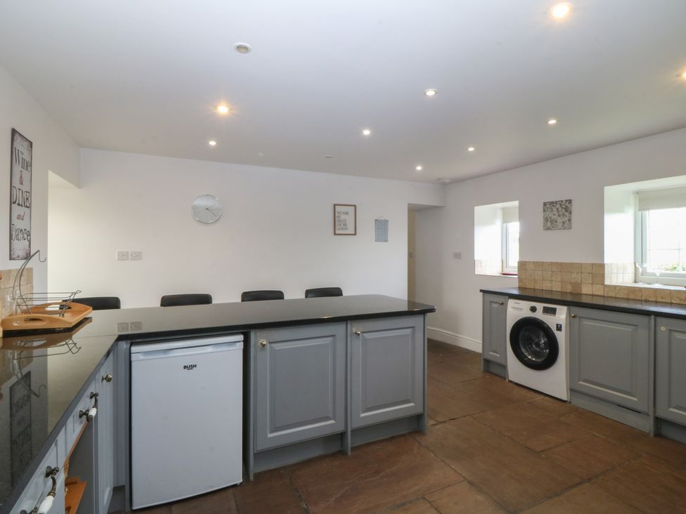A kitchen with counter, refrigerator, washing machine and seating at Llanallgo Church Rooms