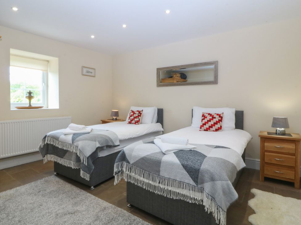 A bedroom with two single beds and a window at Llanallgo Church Rooms