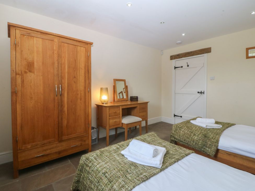 A bedroom with twin beds and wooden furniture at Llanallgo Church Rooms