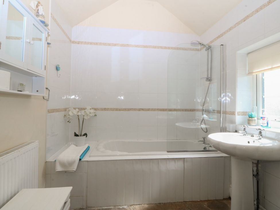 A bathroom with a bathtub, sink, and shower at Llanallgo Church Rooms in 
