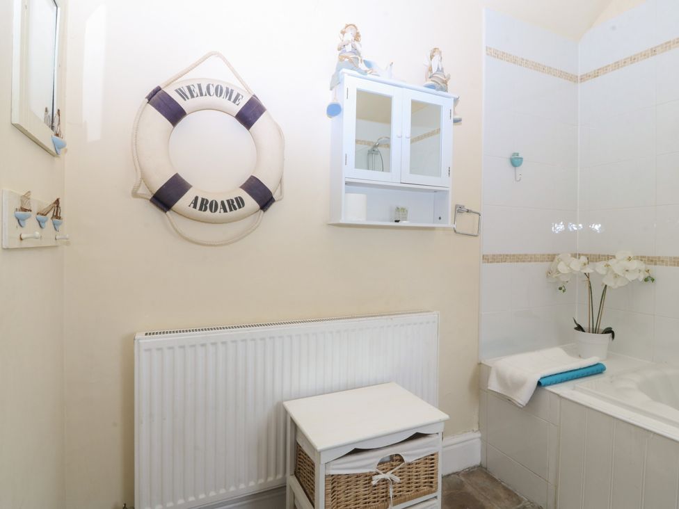 A bathroom with a bathtub and storage at Llanallgo Church Rooms