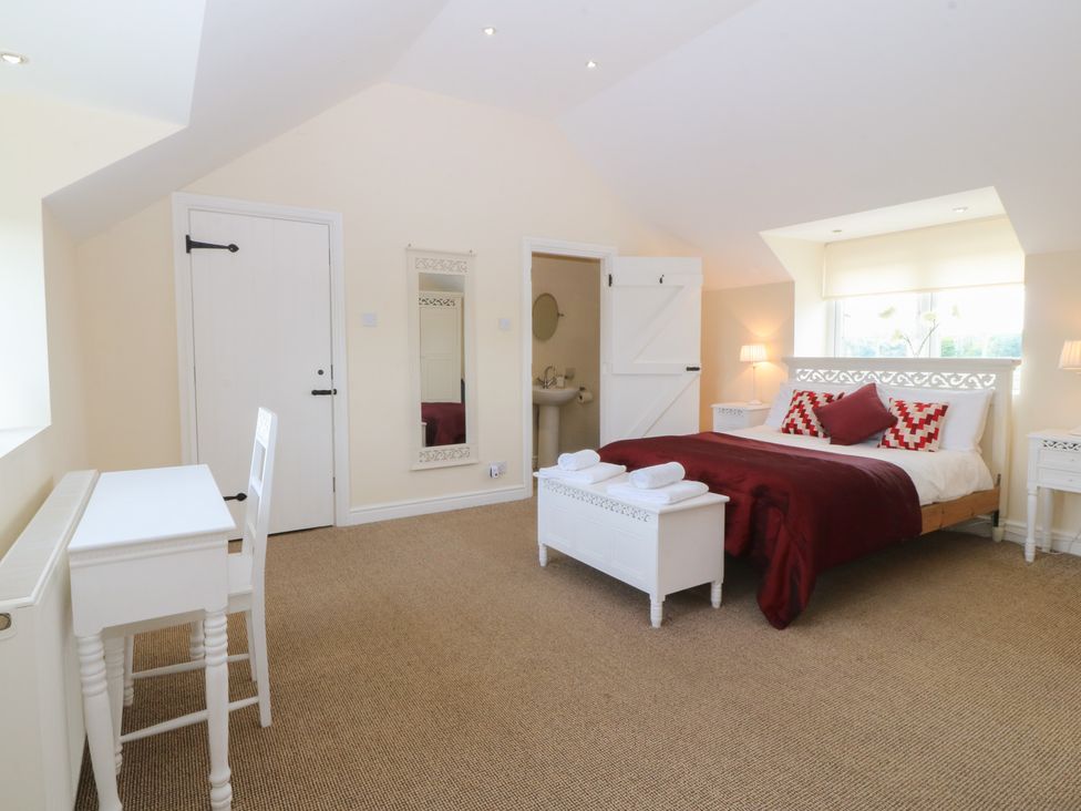 A bedroom with a bed and desk at Llanallgo Church Rooms