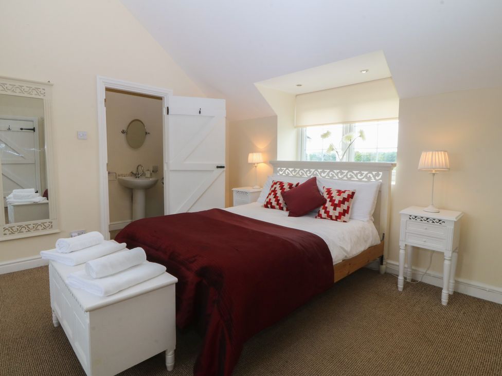 A bedroom with a bed and a mirror at Llanallgo Church Rooms