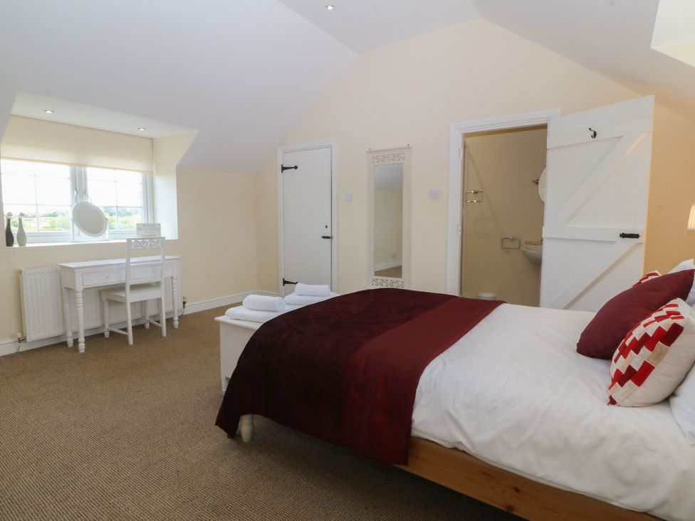 A bedroom with a bed and a table at Llanallgo Church Rooms
