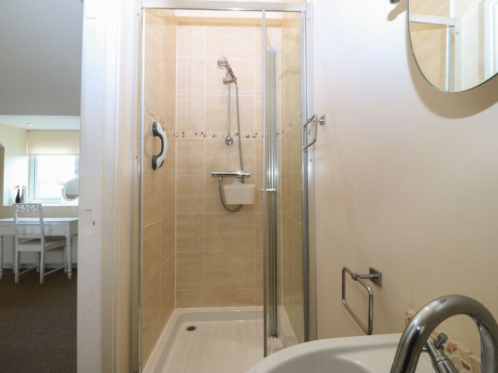 A shower enclosure with a shower head and sink at Llanallgo Church Rooms 