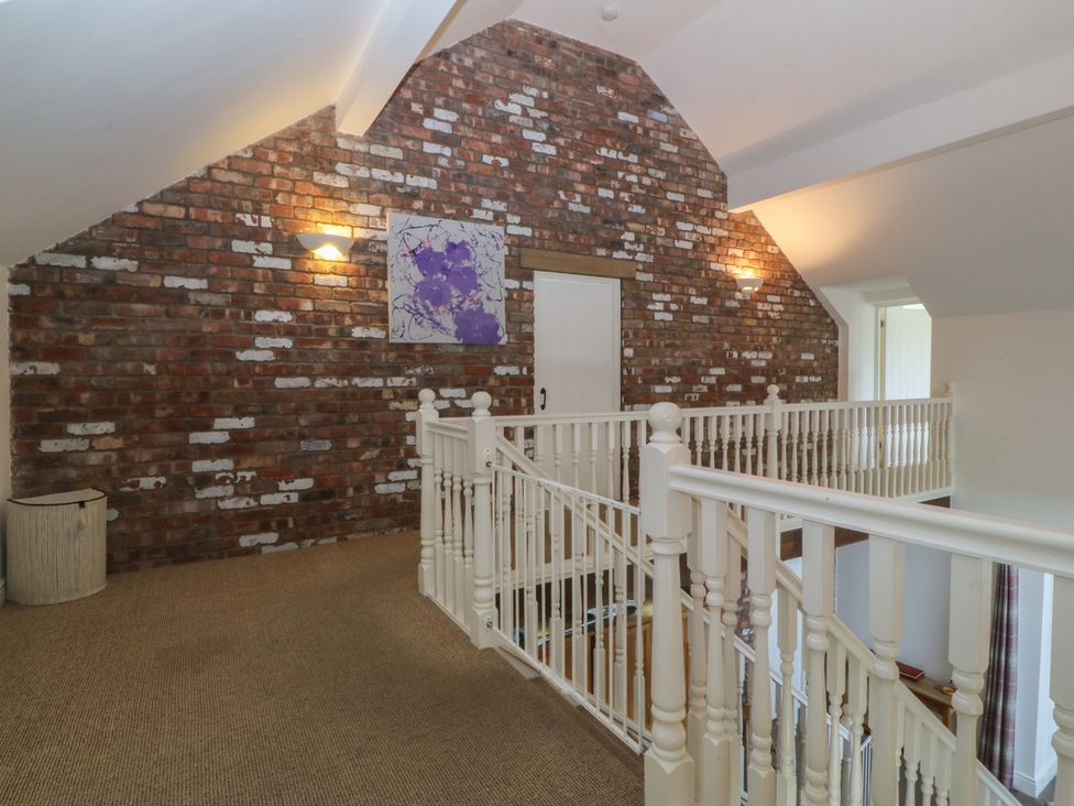 A hallway with a staircase and wall art at Llanallgo Church Rooms 