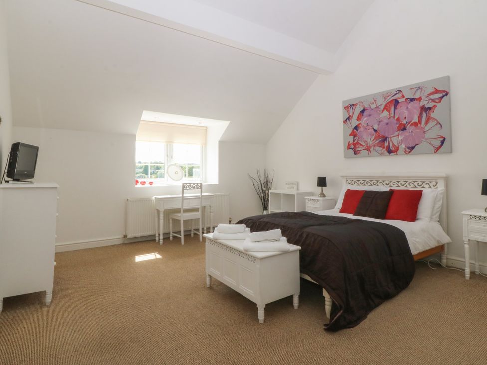 A bedroom with a bed, desk, and television at Llanallgo Church Rooms