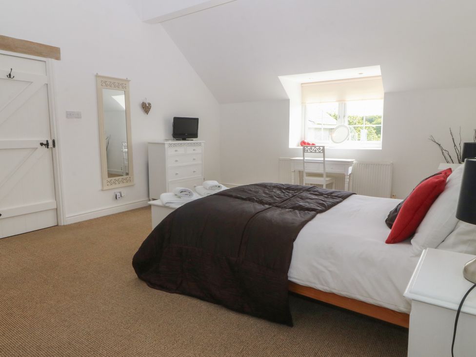 A bedroom with a bed and dresser at Llanallgo Church Rooms 