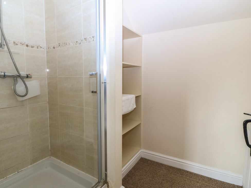 A bathroom with a shower and shelves at Llanallgo Church Rooms