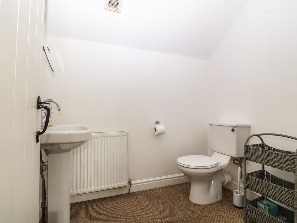 A bathroom with a sink, toilet, and radiator at Llanallgo Church Rooms