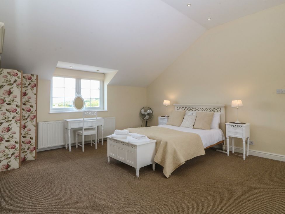 A bedroom with a bed and dresser at Llanallgo Church Rooms