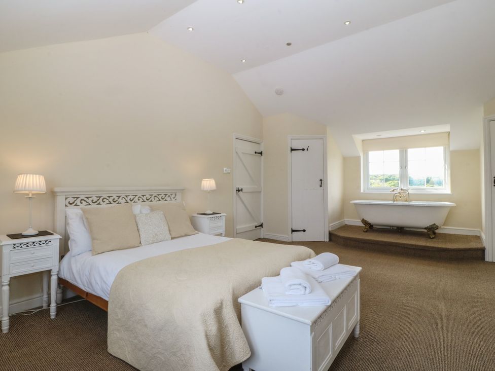 A bedroom with a bed and a bathtub at Llanallgo Church Rooms 