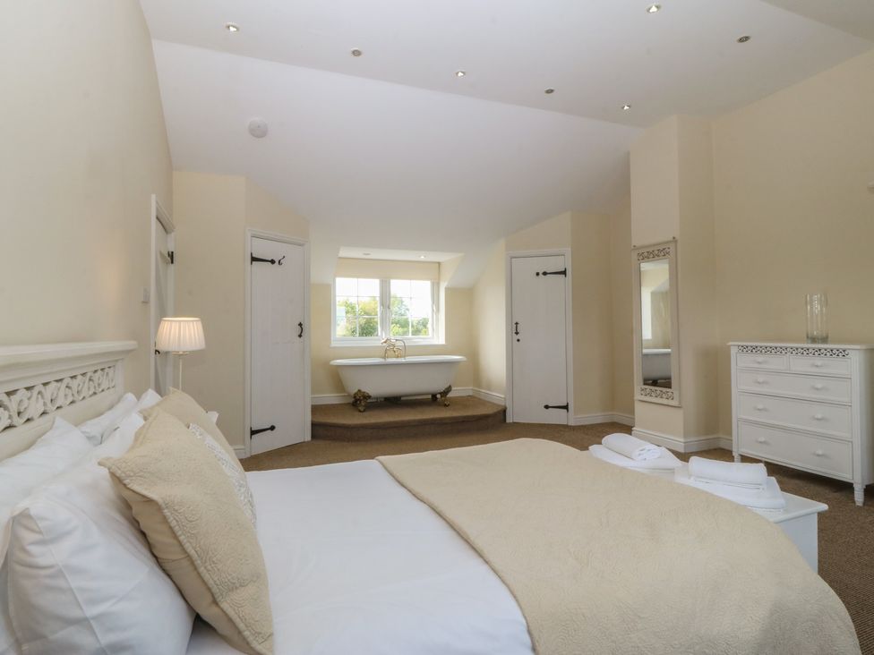 A bedroom with a bathtub and dresser at Llanallgo Church Rooms