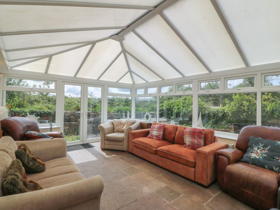 A conservatory with seating and windows at Llanallgo Church Rooms in 