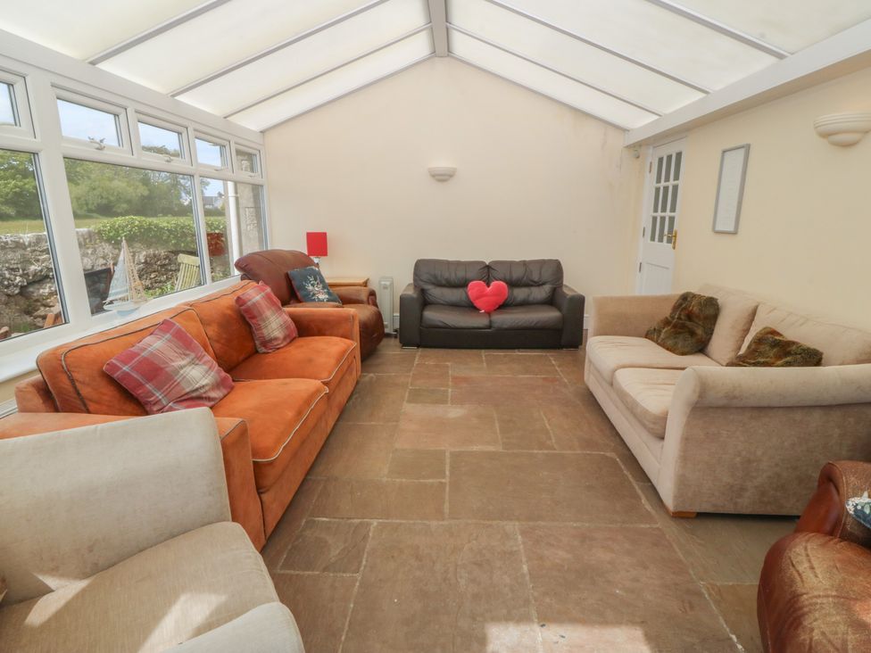 A conservatory with seating and a door at Llanallgo Church Rooms