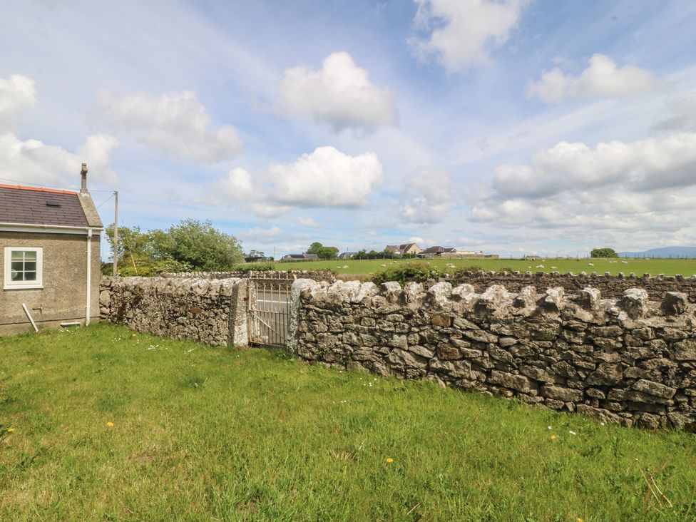 An outdoor view showing a house and a stone wall with a gate in Llanallgo Church Rooms 