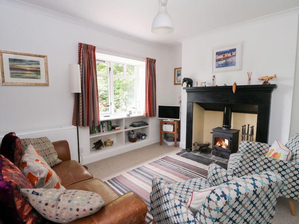 A living room with a sofa, armchair, fireplace and television at Tower Lodge in Lochawe
