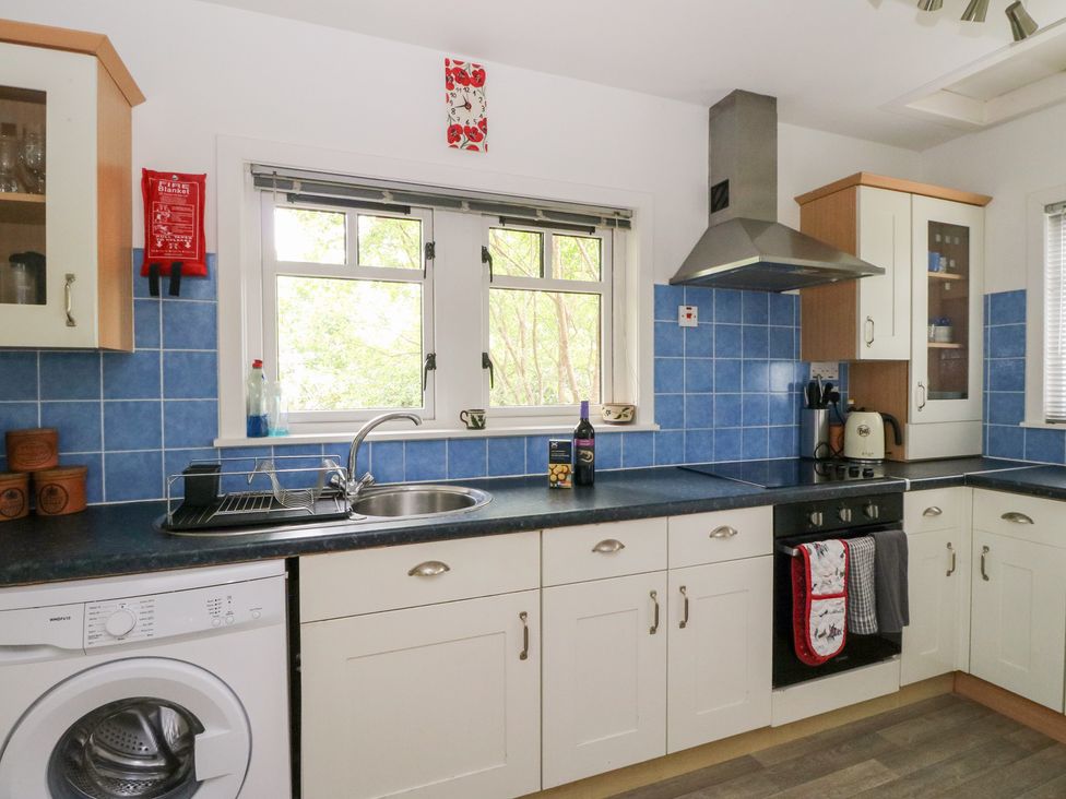 A kitchen with cabinets and washing machine at Tower Lodge in Lochawe