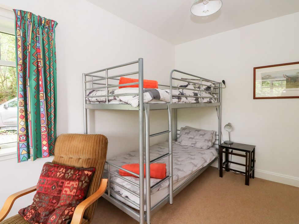 A bedroom with a bunk bed and a chair at Tower Lodge in Lochawe