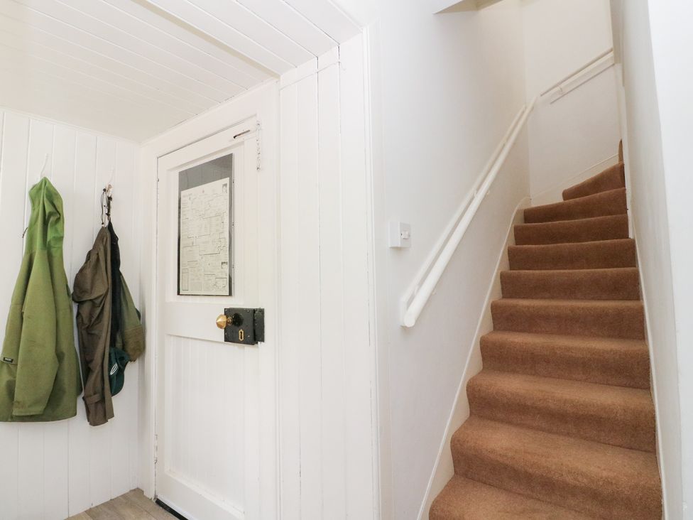 A hallway with coats on hooks and a staircase at Tower Lodge in Lochawe