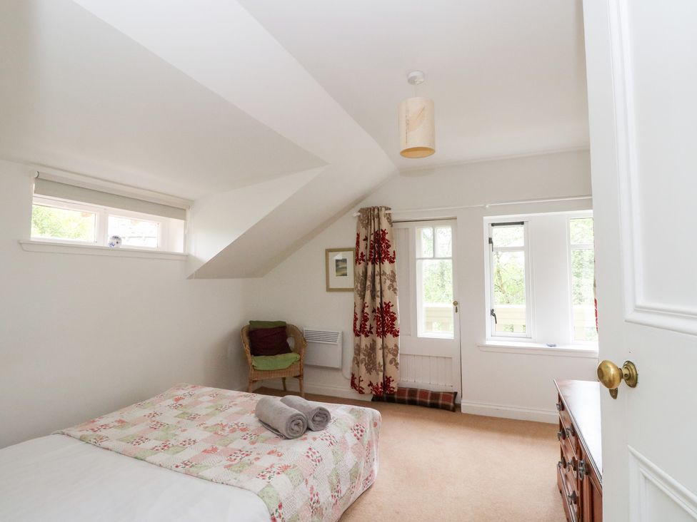 A bedroom with a bed and a chair at Tower Lodge in Lochawe