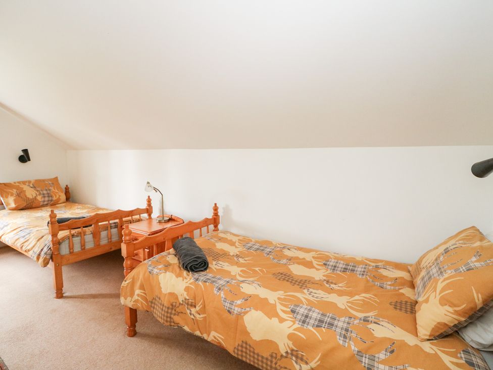 A bedroom with two beds and a lamp at Tower Lodge Lochawe