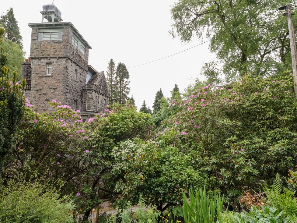 A stone building surrounded by trees and bushes at Tower Lodge in Lochawe