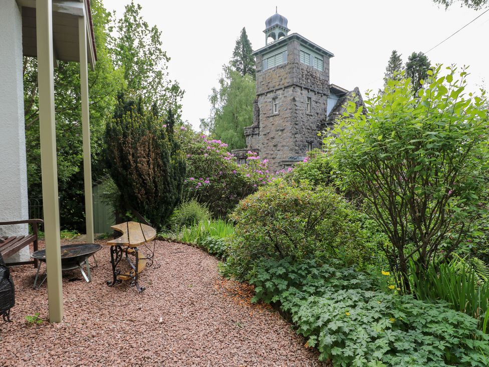 A garden with a bench and table next to a stone building at Tower Lodge in Lochawe