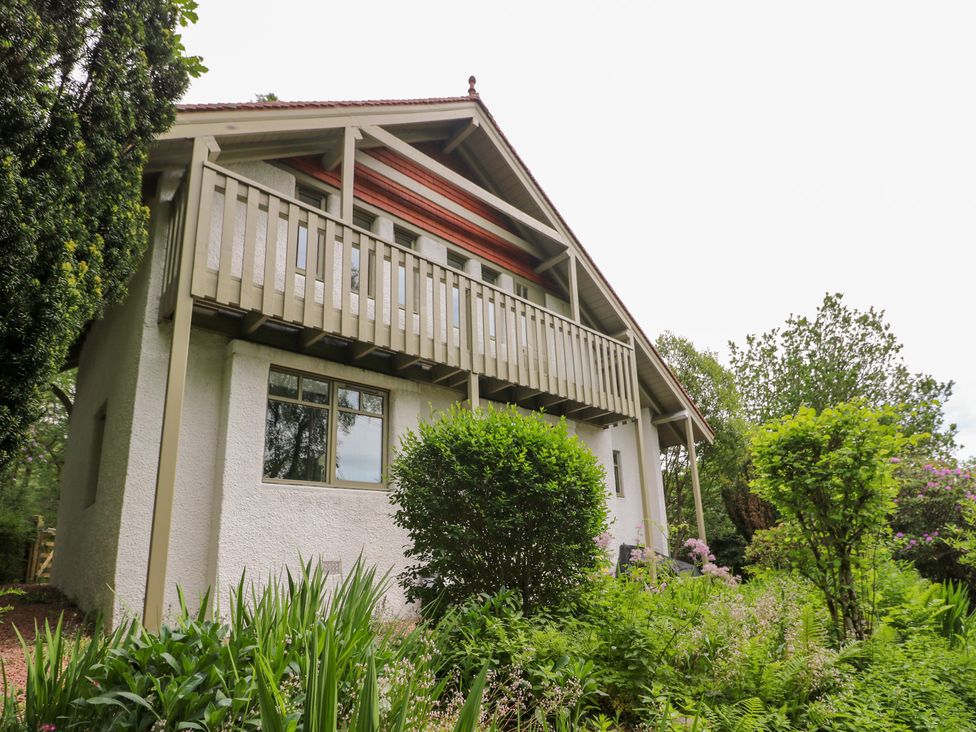 A house with a balcony and surrounding vegetation at Tower Lodge in Lochawe