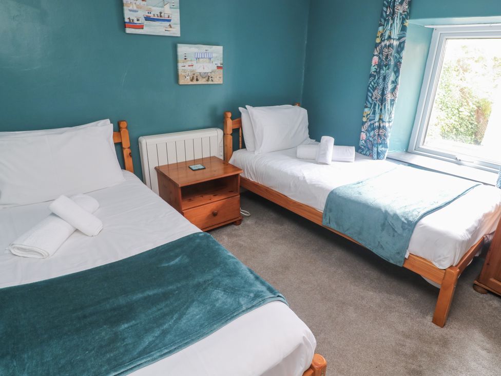 A bedroom with two beds and a table at Pebble Cottage in Portreath