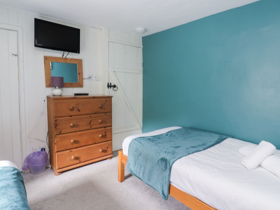 A bedroom with two beds and a dresser at Pebble Cottage Portreath