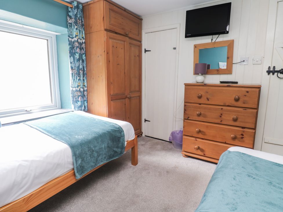 A bedroom with two beds and furniture at Pebble Cottage in Portreath