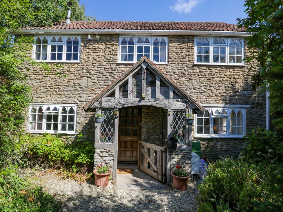 An exterior view of a stone cottage with windows and a wooden door at Ivy Cottage Woolverton near Beckington