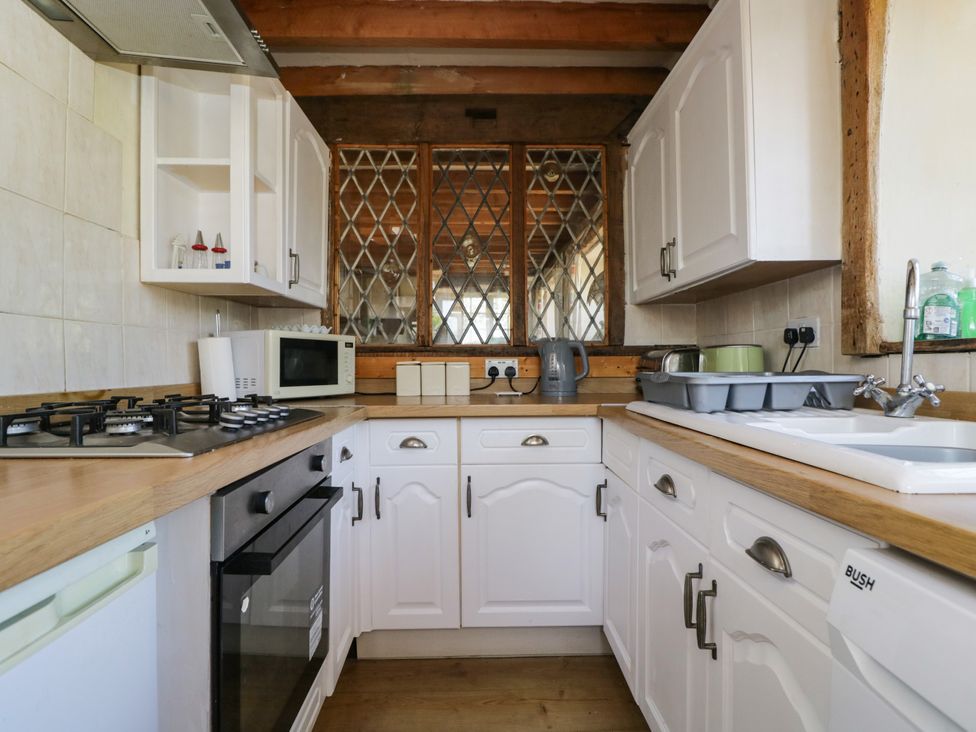 A kitchen with appliances and cabinets at Ivy Cottage in Woolverton near Beckington