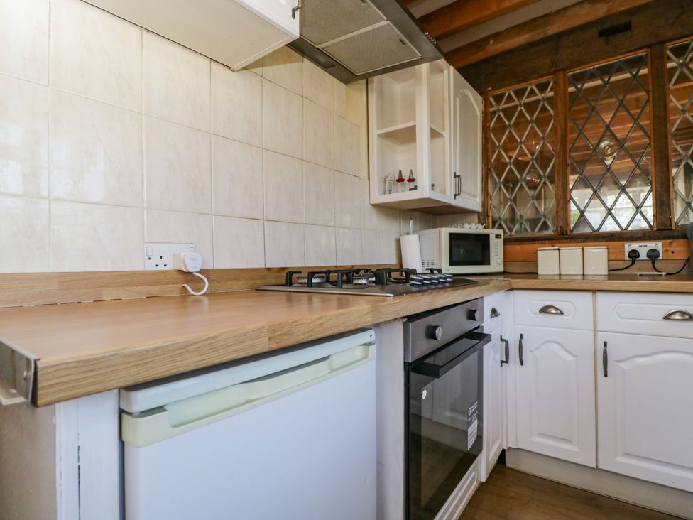 A kitchen with a gas stove and microwave at Ivy Cottage in Woolverton near Beckington