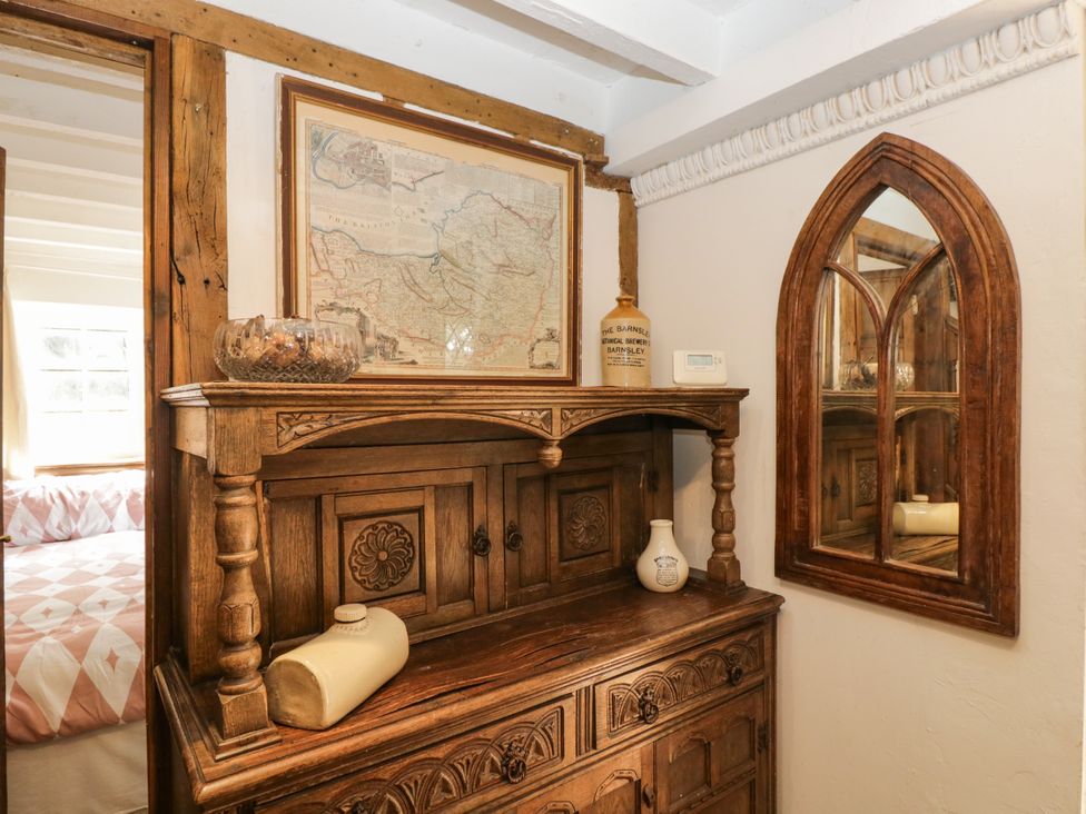 A bedroom with a wooden cabinet and a mirror at Ivy Cottage in Woolverton near Beckington