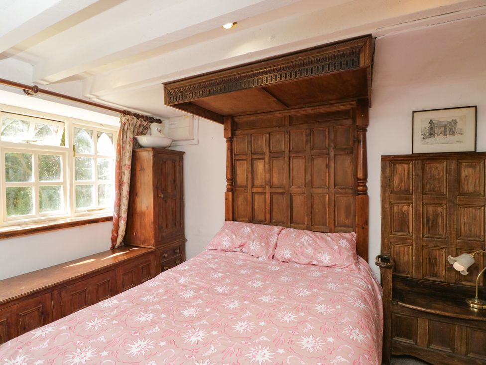 A bedroom with a wooden bed and chest of drawers at Ivy Cottage Woolverton near Beckington