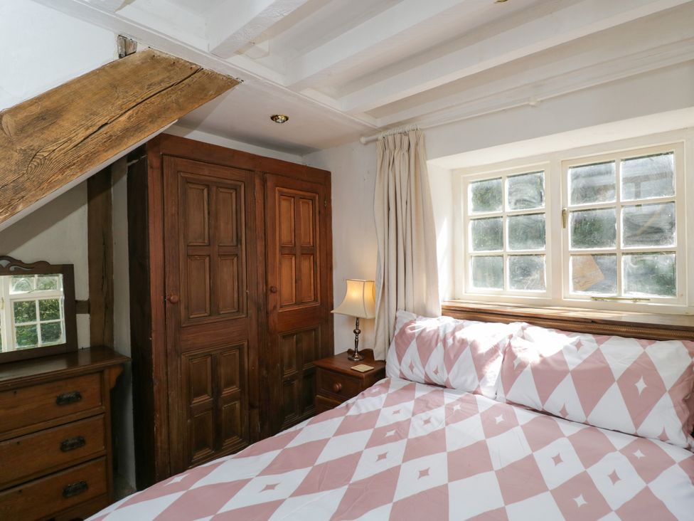 A bedroom with a bed, wardrobe, and window at Ivy Cottage in Woolverton near Beckington